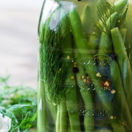 Pickled green beans in a glass jar, with a text overlay.