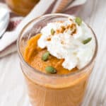 Close up view of easy pumpkin pudding garnished with whipped cream, pepitas, and cinnamon.