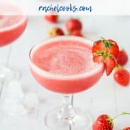 Frozen Rosé in a stemmed glass, garnished with strawberries, strawberries also scattered around.