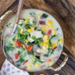 Close up overhead view of chicken corn chowder, in a two-handled bowl, with a spoon.