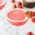 Frozen Rosé wine blended with strawberries in a stemmed glass, garnished with strawberries.