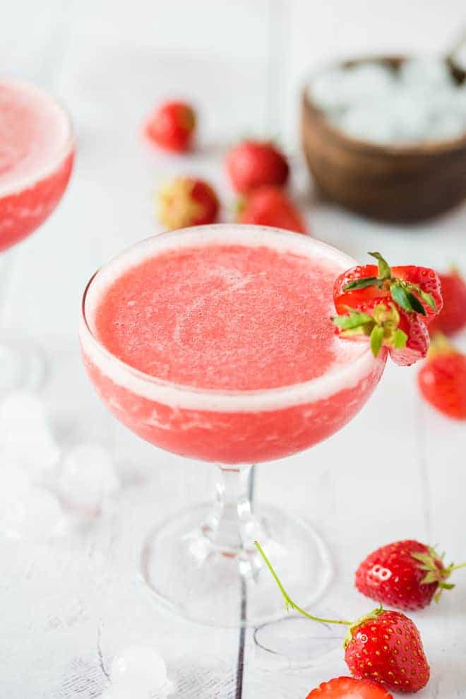 Frozen Rosé wine blended with strawberries in a stemmed glass, garnished with strawberries.