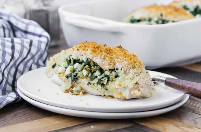 Landscape view of a spinach and feta stuffed chicken breast with panko breading. A baking dish is also pictured in the background.