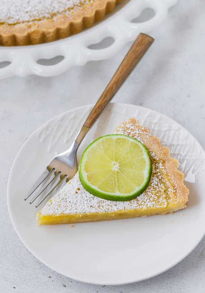 Slice of a lemon lime tart on a round white plate.