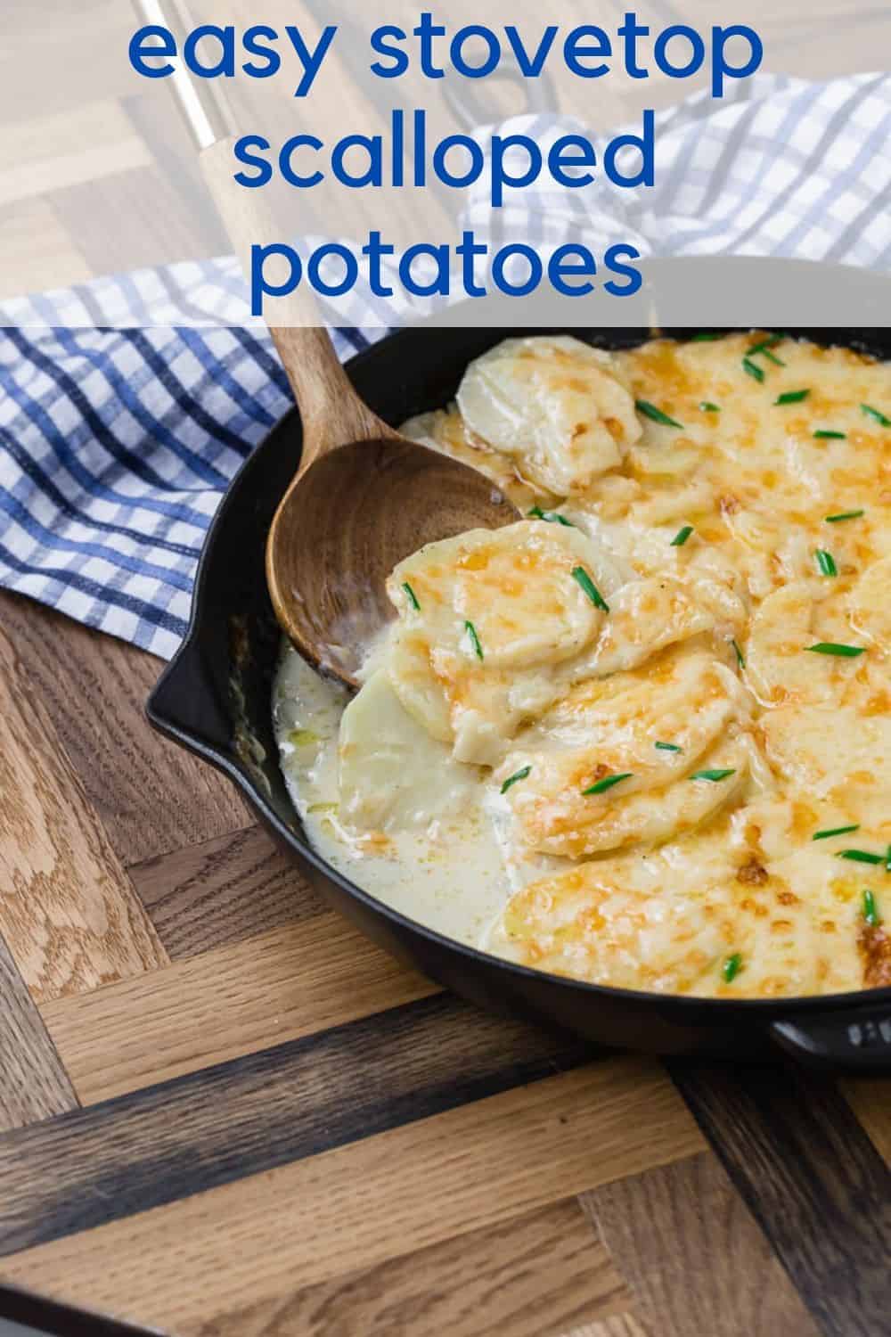 Scalloped potatoes in a skillet on a wooden background. Text overlay with recipe title.