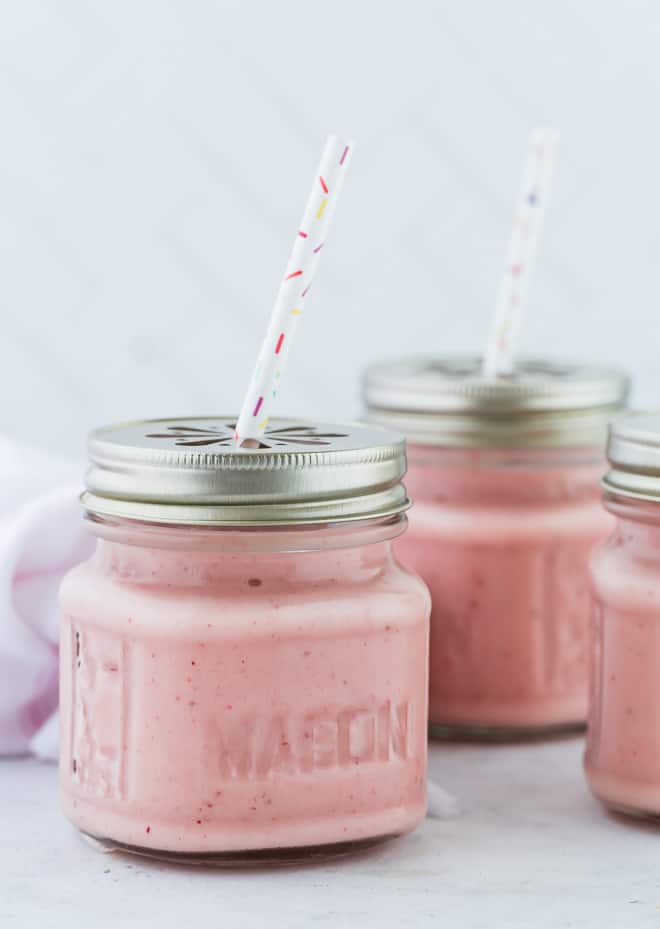 Three smoothies in small glass jars with lids.
