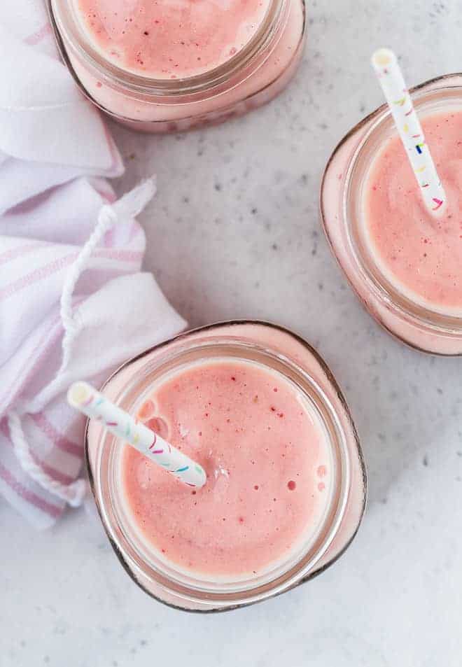 Overhead view of small three jars of a light pink fruit smoothie.