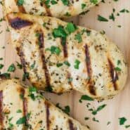 Grilled chicken breasts on a wooden cutting board. Text overlay reads "Italian Chicken Marinade."