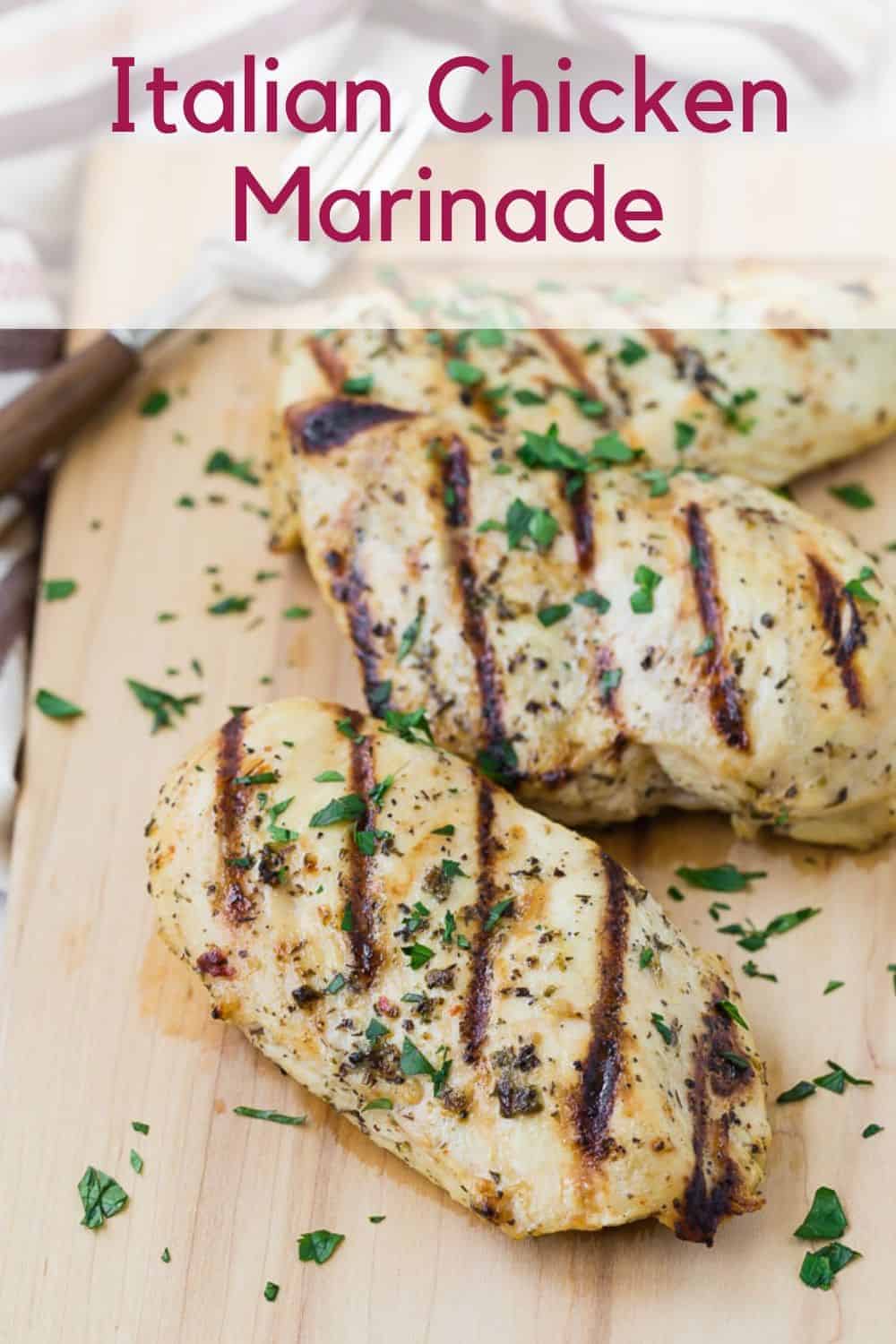 Grilled chicken breasts on a wooden cutting board. Text overlay reads "Italian Chicken Marinade."