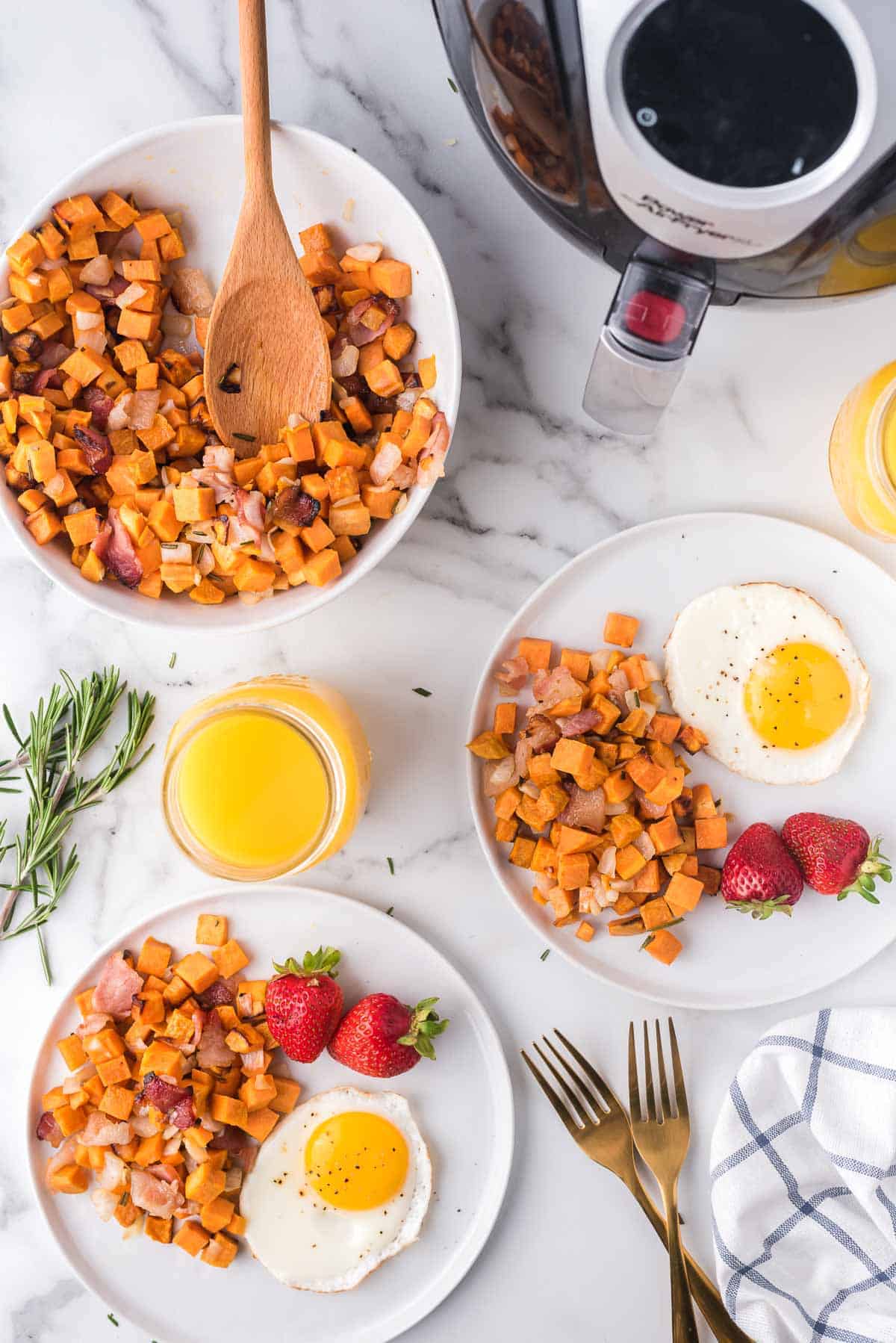 Overhead view of breakfast comprised of sweet potato hash, eggs, strawberries and coffee.