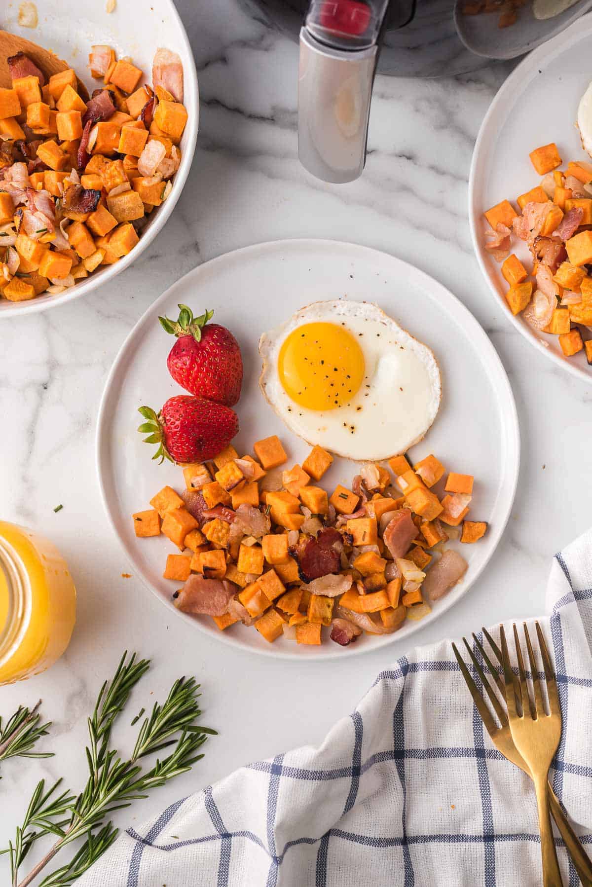 Plate of sweet potato hash, a fried egg, and whole strawberries.