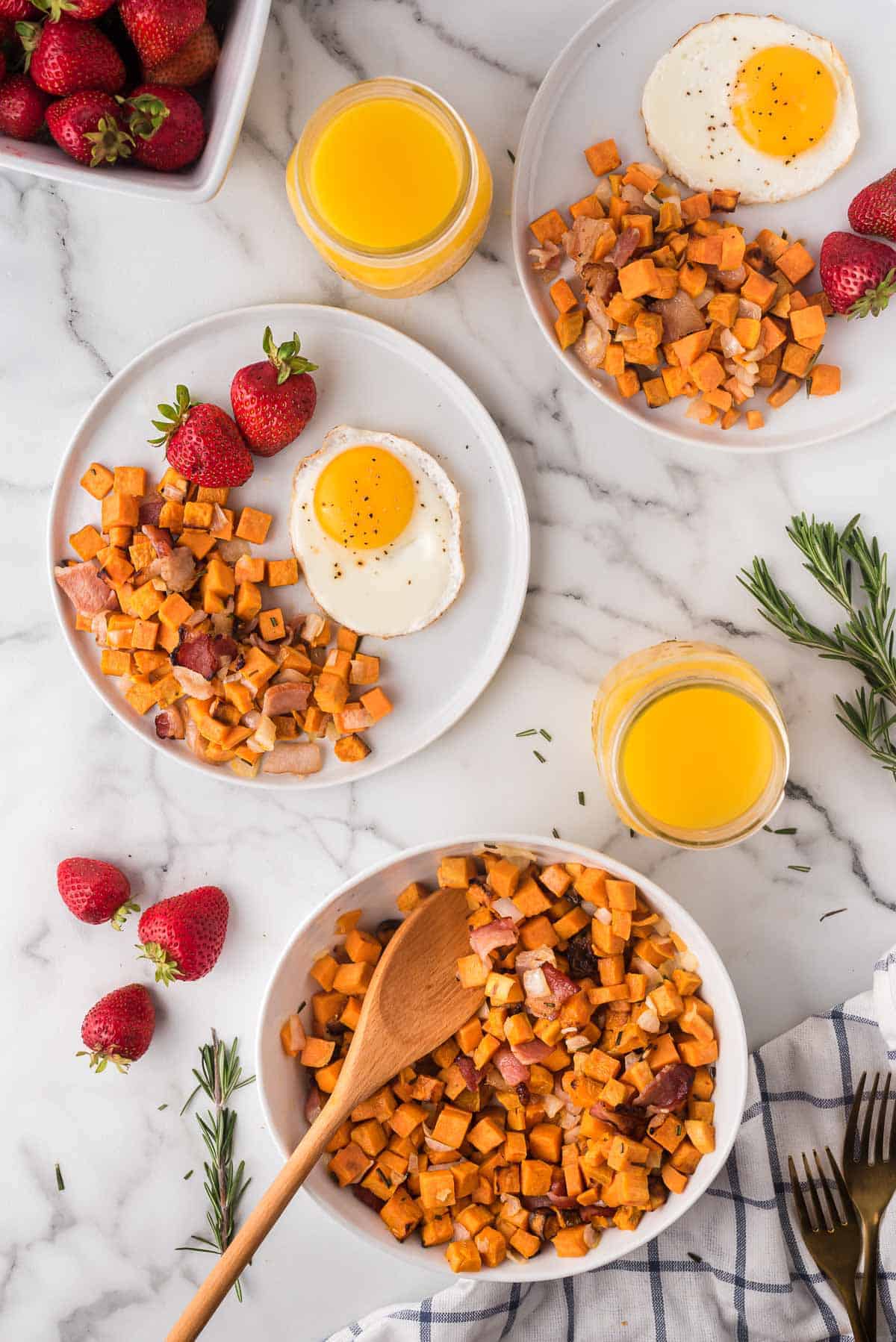 Overhead view of two plates and a bowl of air fryer sweet potato hash.