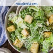 A jar of caesar salad dressing in front of a tossed salad. A text overlay reads "healthy caesar salad dressing."