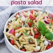 A white bowl full of pasta, fresh mozzarella, tomatoes, and fresh basil. A text overlay reads "the best caprese pasta salad."