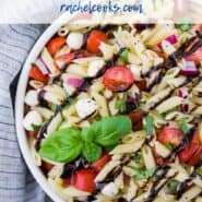 A white bowl full of pasta, fresh mozzarella, tomatoes, and fresh basil. A text overlay reads "caprese pasta salad - rachelcooks.com"