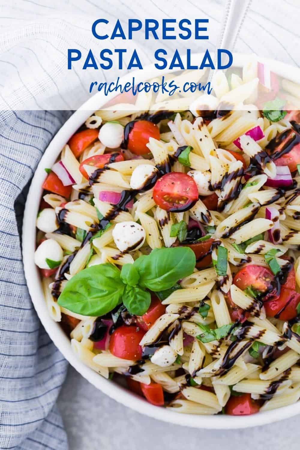 A white bowl full of pasta, fresh mozzarella, tomatoes, and fresh basil. A text overlay reads "caprese pasta salad - rachelcooks.com"