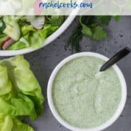 Green and white salad dressing in a white bowl with a black spoon. Text overlay reads "healthy green goddess salad dressing."