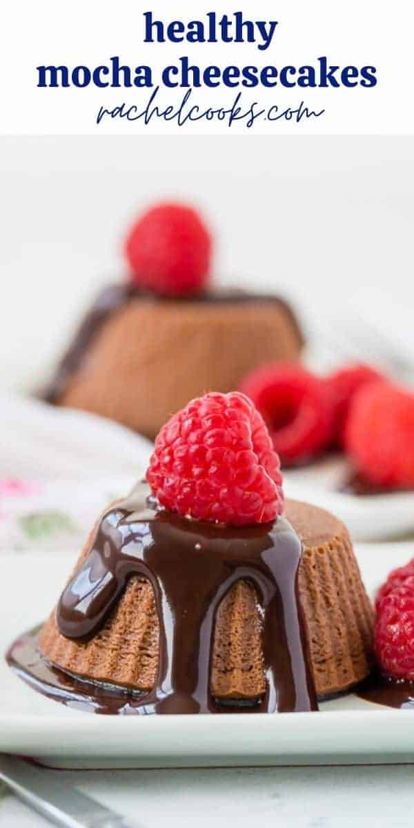 Small chocolate cheesecakes topped with chocolate syrup and raspberries.