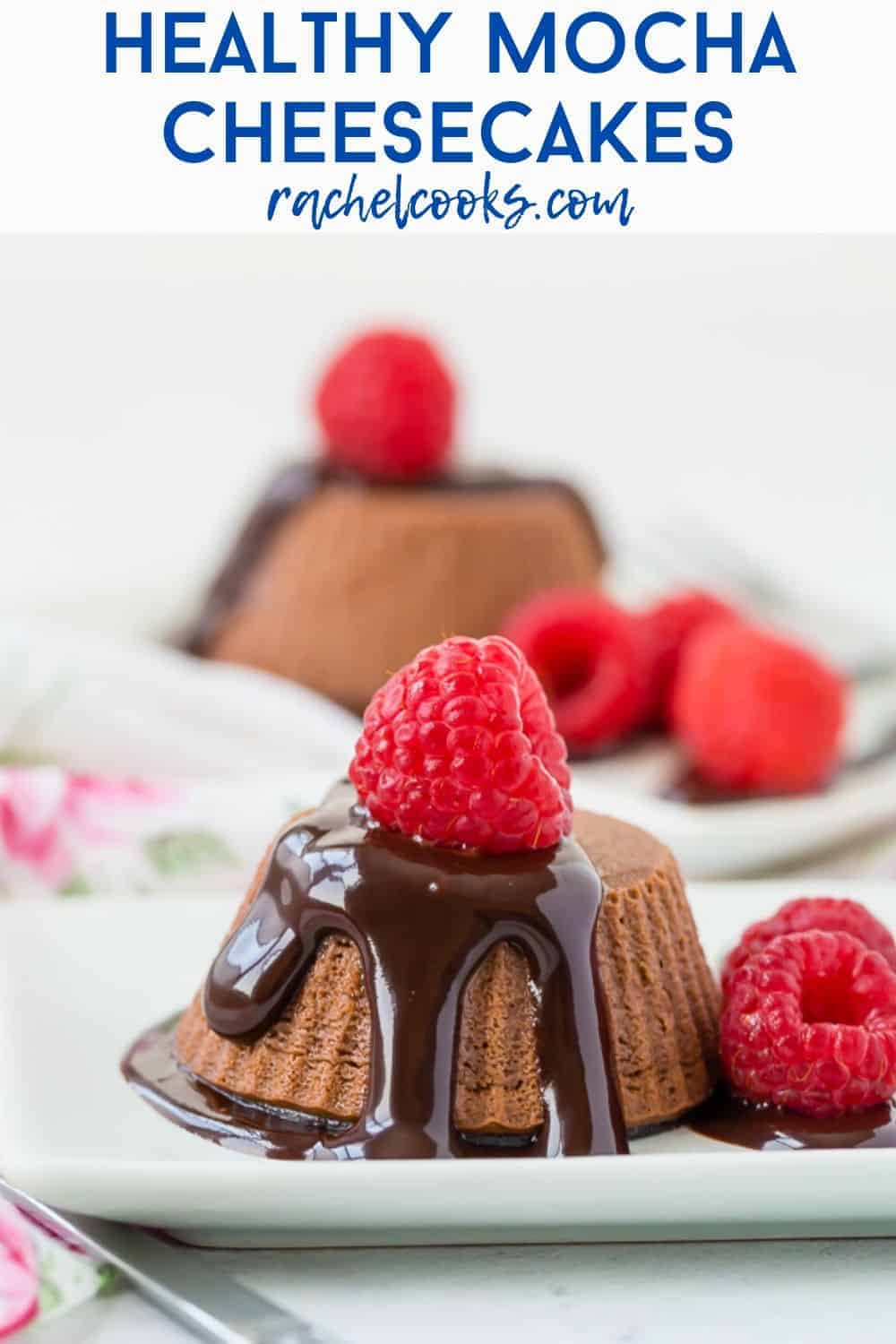 Small chocolate cheesecakes topped with chocolate syrup and raspberries.