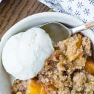 Overhead view of plated peach dessert, with ice cream. Text overlay reads "easy peach crumble."