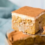 Pumpkin poke cake being scooped out of a baking dish.