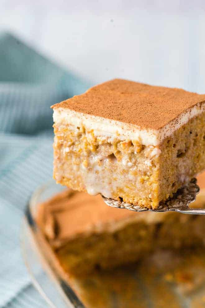 Pumpkin poke cake being scooped out of a baking dish.