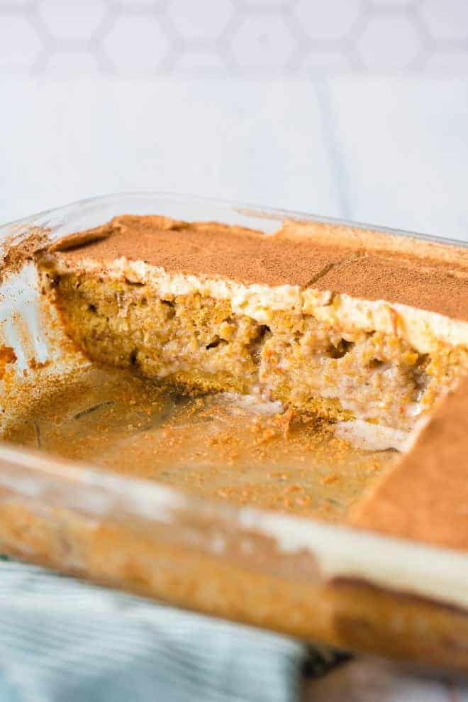 Pumpkin poke cake in a clear baking dish, with slices missing.