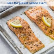 Three salmon fillets on a parchment paper lined sheet pan. Each is topped with pepper and a lemon wedge. Text overlay reads "slow roasted salmon, aka the juiciest salmon ever."