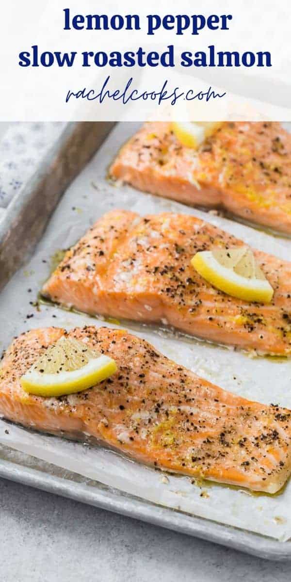 Three slow roasted salmon filets topped with lemon slices and black pepper on a parchment lined baking sheet.