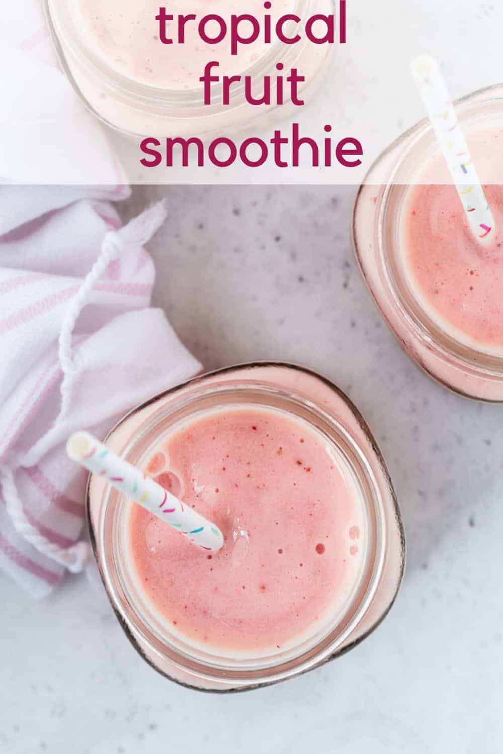Overhead view of a pink fruit smoothie with fun sprinkles straws.