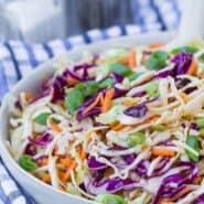 Colorful coleslaw in a white bowl with a blue and white linen.