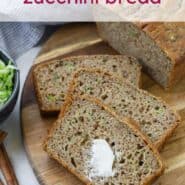 Overhead view of sliced zucchini bread, with a dab of butter on it. A text overlay reads "whole wheat zucchini bread."