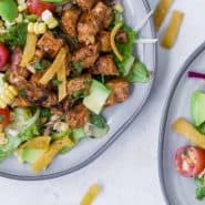 Colorful chopped salad on a plate - includes bbq chicken, avocado, tomatoes, corn, onion. Text overlay reads "bbq chicken chopped salad."