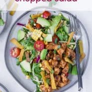 Colorful chopped salad on a plate - includes bbq chicken, avocado, tomatoes, corn, onion. Text overlay reads "bbq chicken chopped salad."