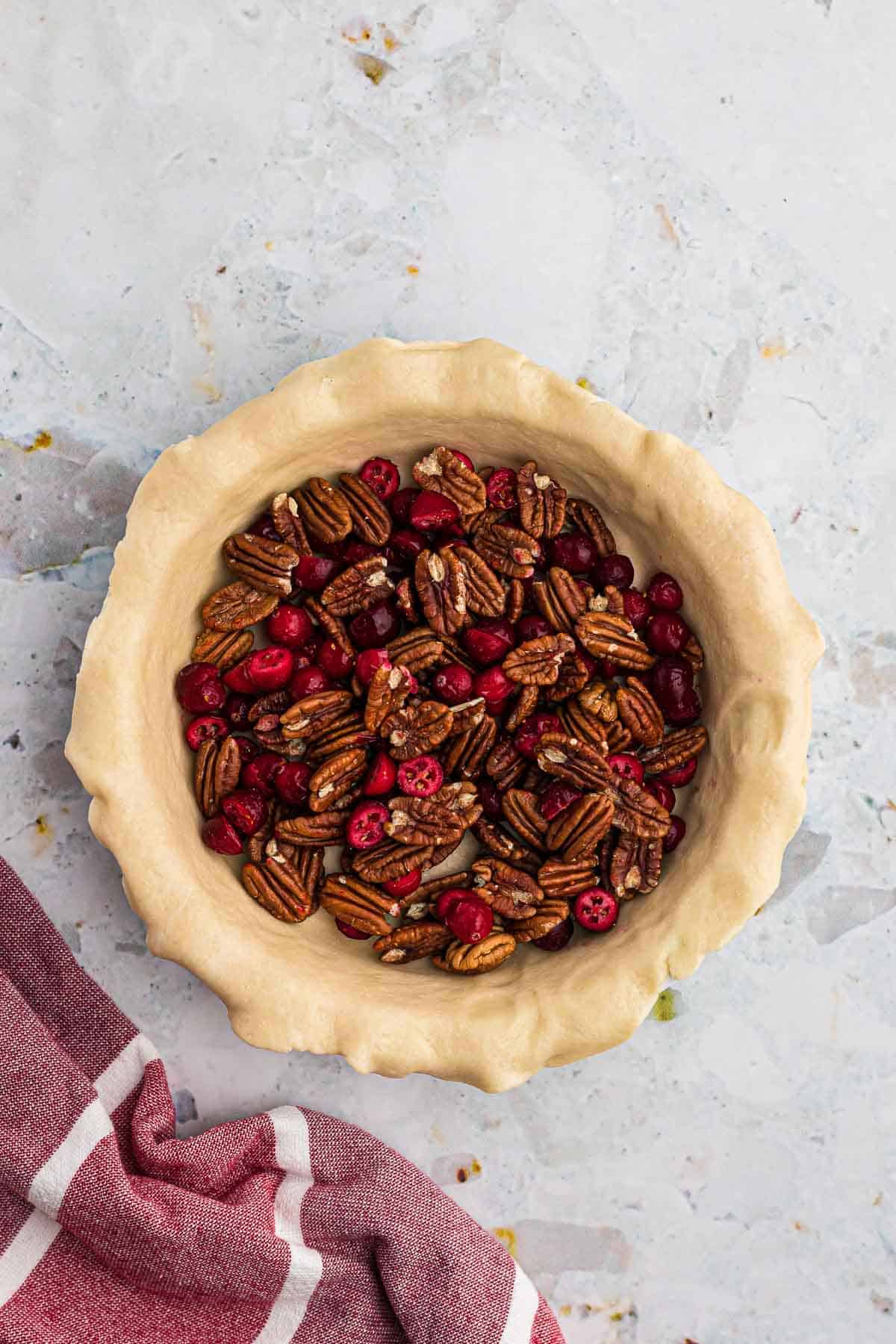 Pecans and cranberries in an unbaked pie crust.