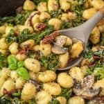 Close-up view of one pan gnocchi on a serving spoon. Sun-dried tomatoes are also visible.