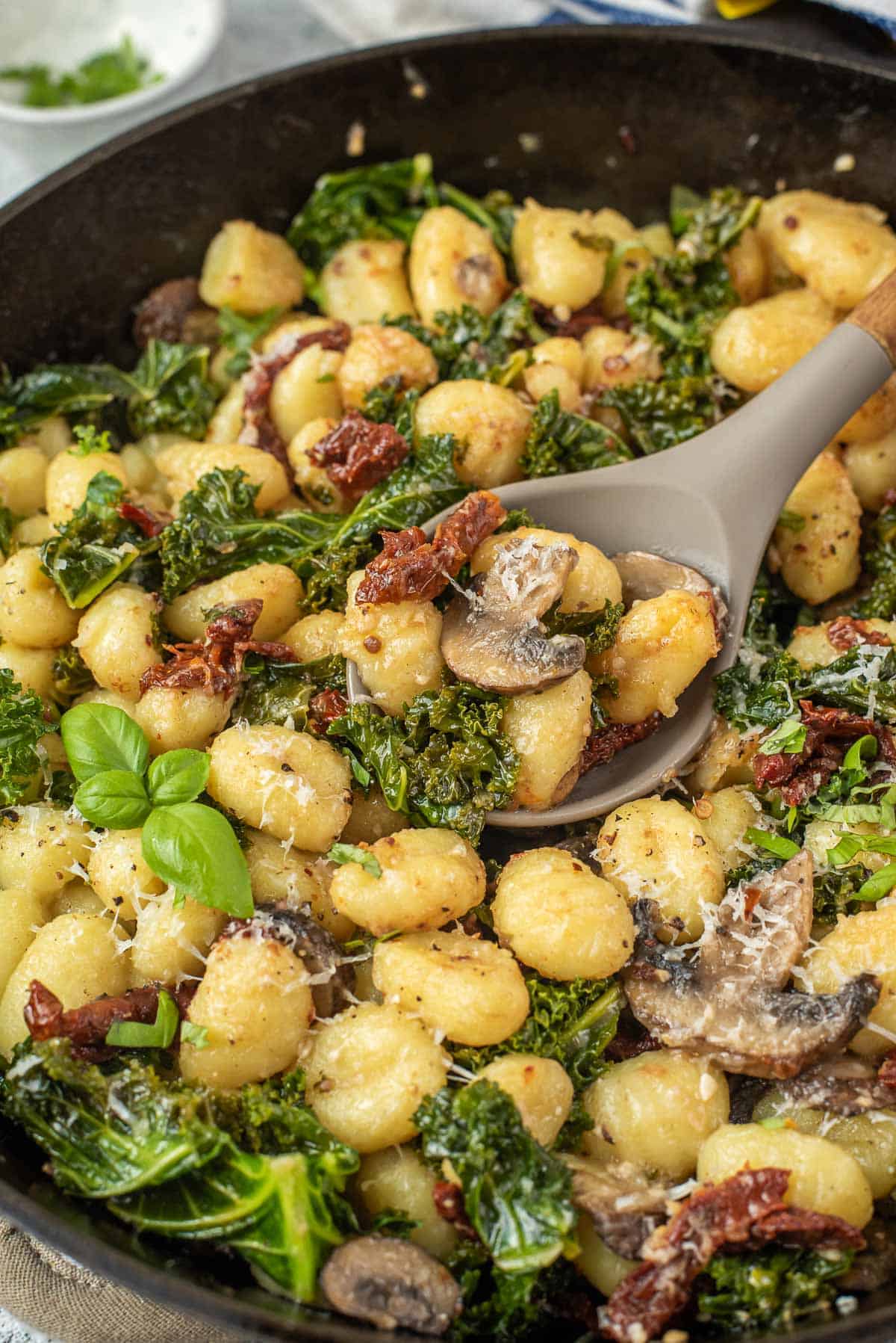 Close-up view of one pan gnocchi on a serving spoon. Sun-dried tomatoes are also visible.