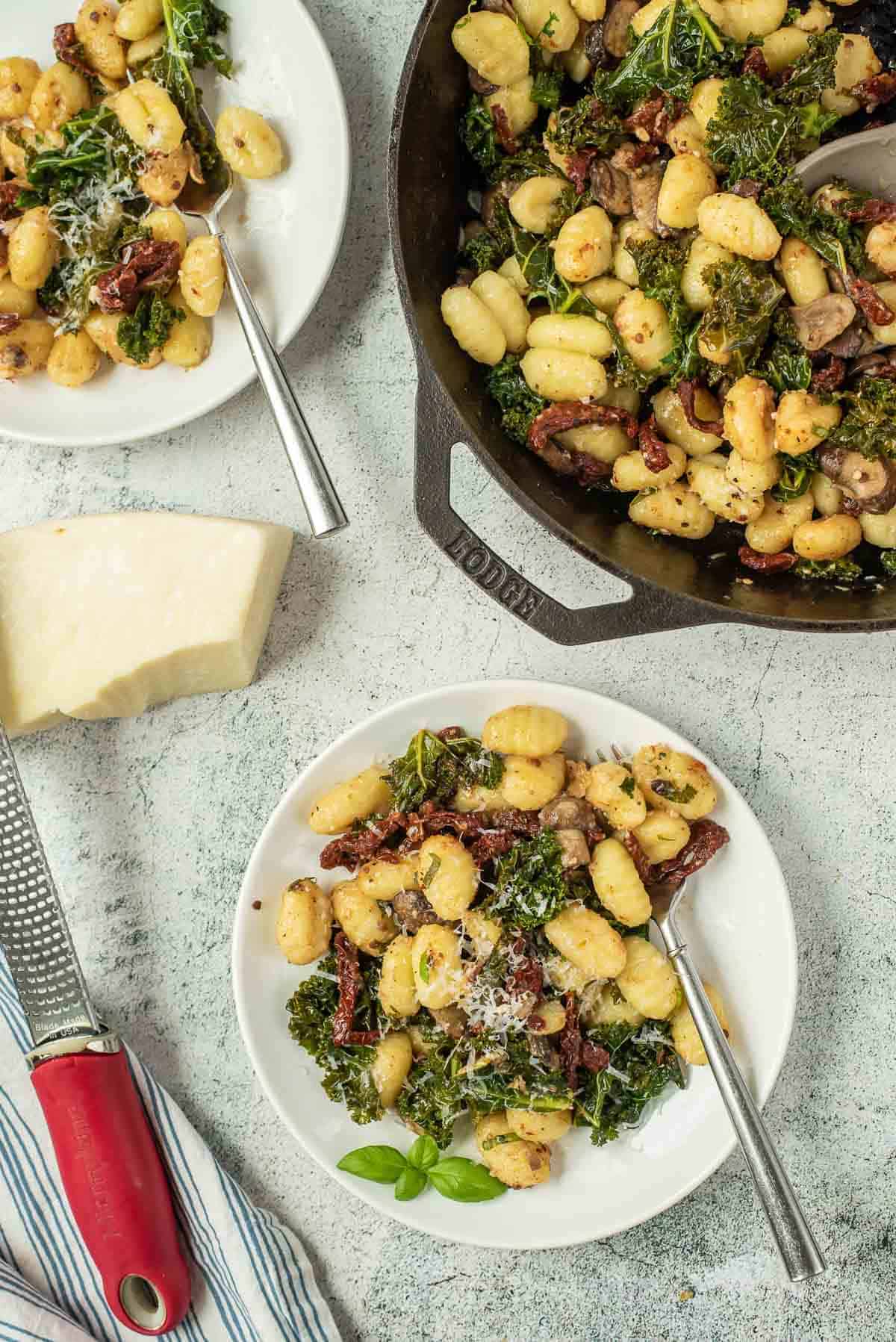 Overhead view of gnocchi with sun-dried tomatoes, kale, and mushrooms.