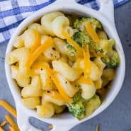 Overhead view of a small white bowl full of pasta and broccoli. Text overlay reads "instant pot broccoli mac and cheese"