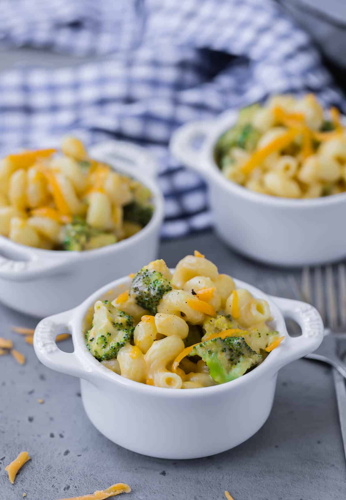 Three small white crocks of broccoli mac and cheese.