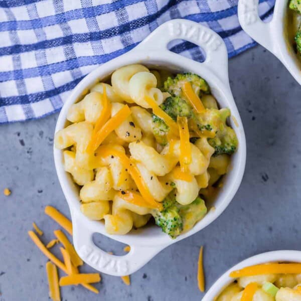 Overhead view of a small white bowl of instant pot mac and cheese with broccoli. Two other bowls are partially visible.