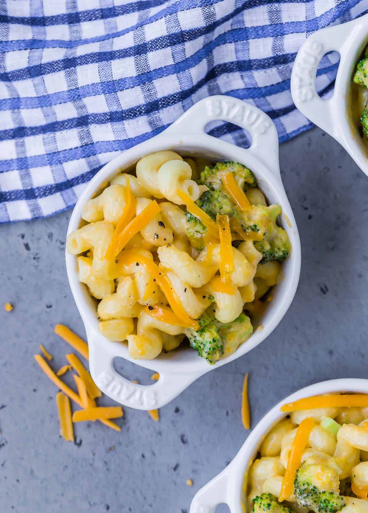 Overhead view of a small white bowl of instant pot mac and cheese with broccoli. Two other bowls are partially visible.