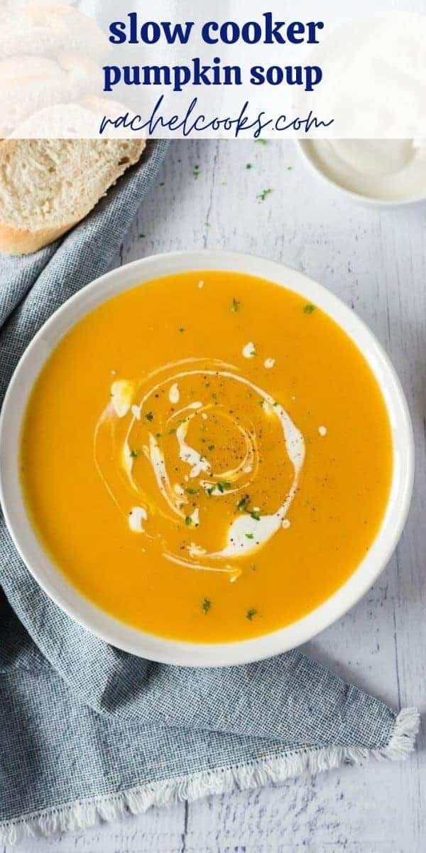 Overhead view of pumpkin soup in a white bowl. Text overlay reads "slow cooker pumpkin soup: rachelcooks.com"