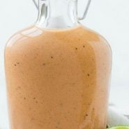 Small glass bottle of sweet bbq salad dressing on a wooden cutting board. Text overlay reads "sweet bbq dressing"