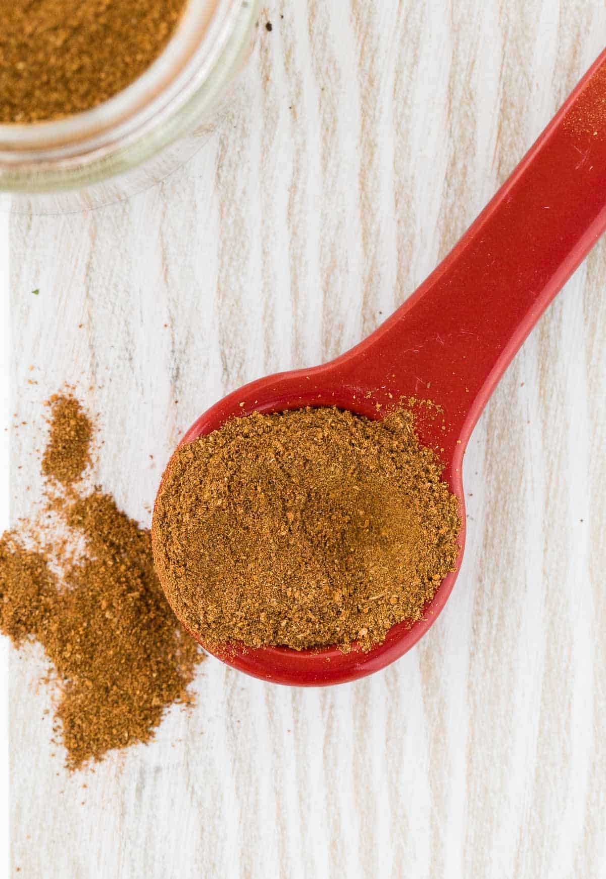 Close up of spices on a red measuring spoon.