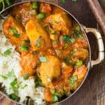 Close up of chicken served with rice, carrots, and a creamy tomato sauce. It is served in a small bowl with rice and cilantro.