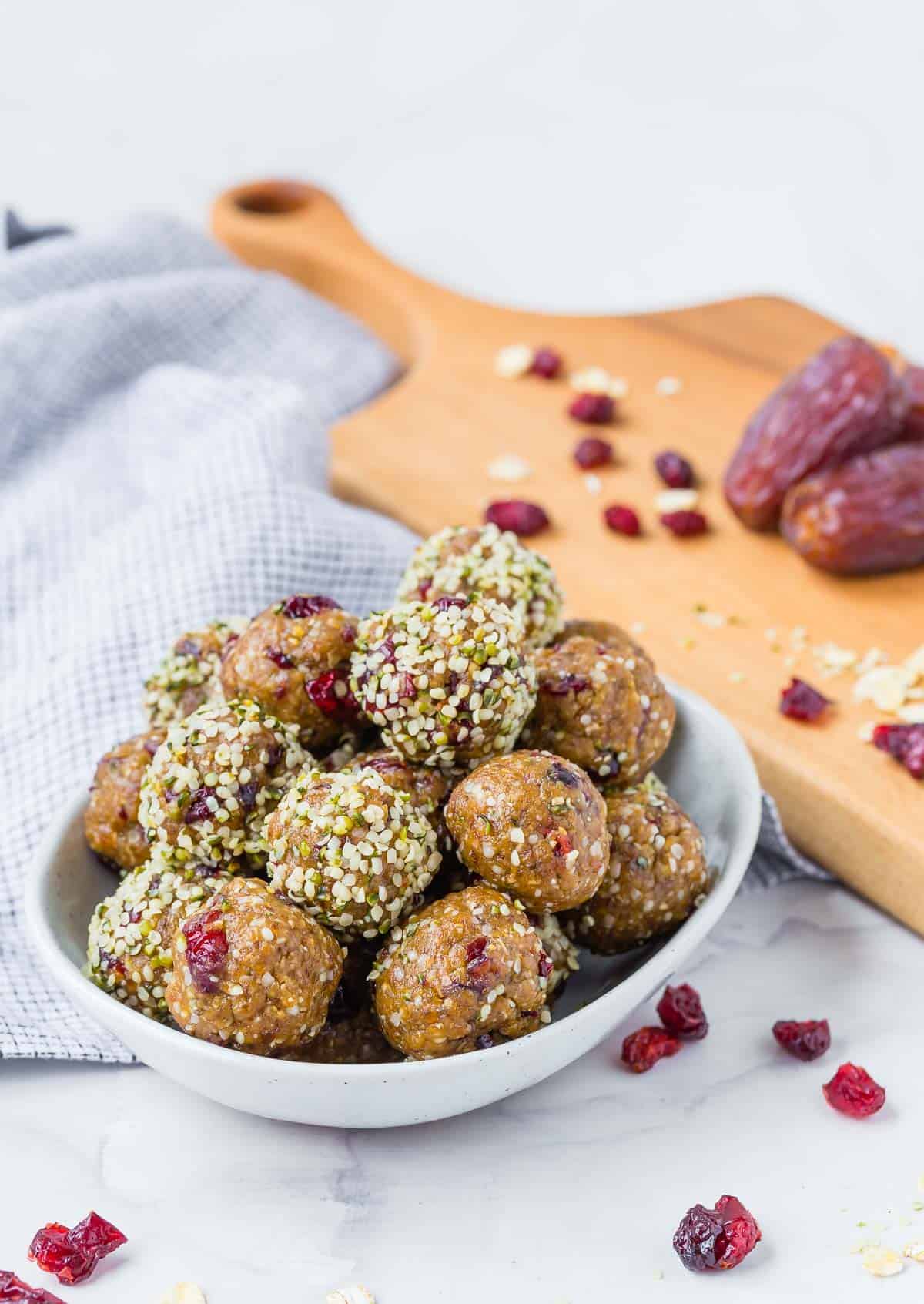 A bowl of energy bites with dried cranberries, dates, and oats in the background.