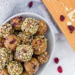 Overhead view of bowl of energy bites, with dried cranberries, oats and hemp seeds also pictured.