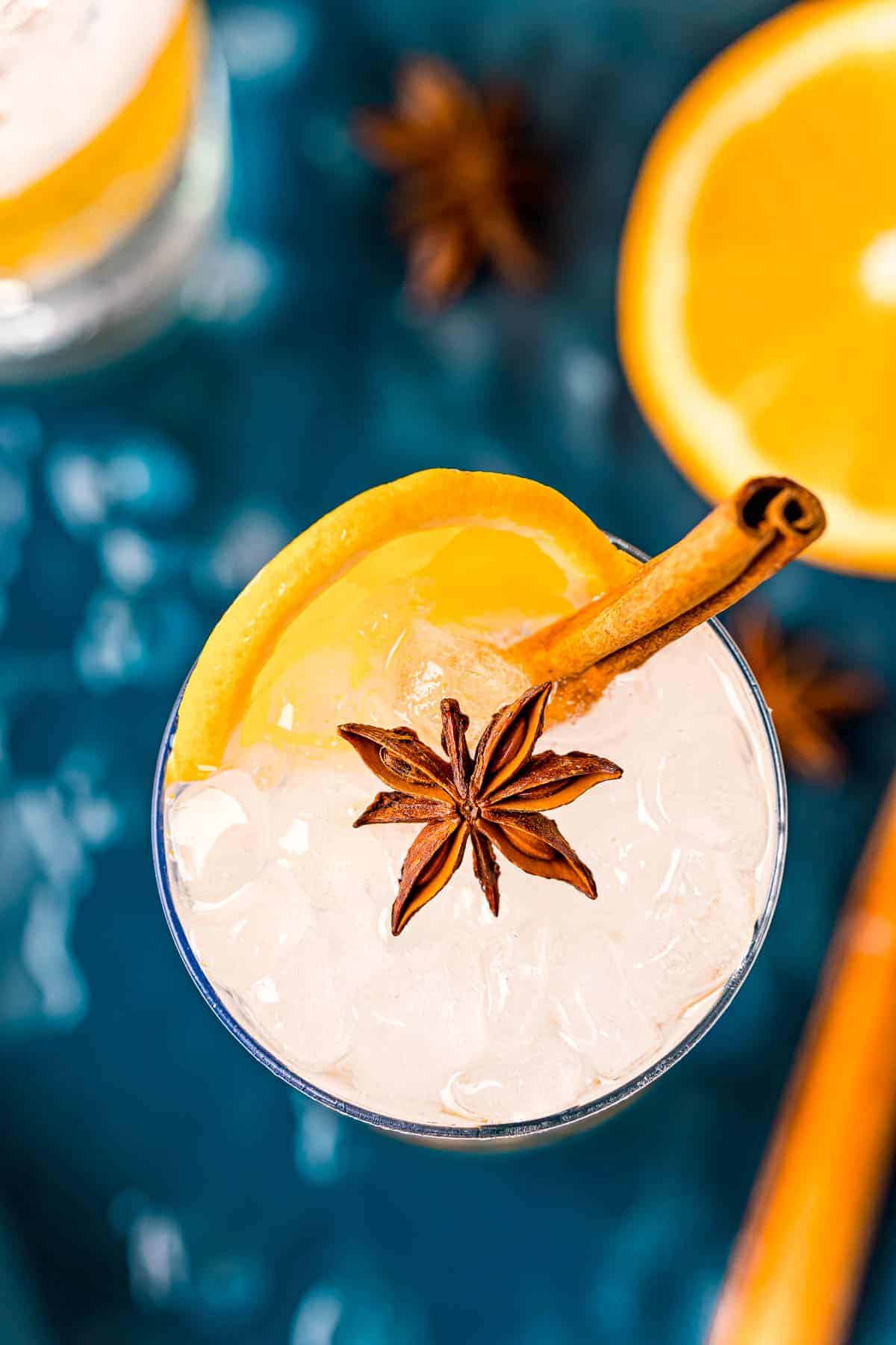 Overhead view of gin cocktail with an orange slice, cinnamon stick and star anise.