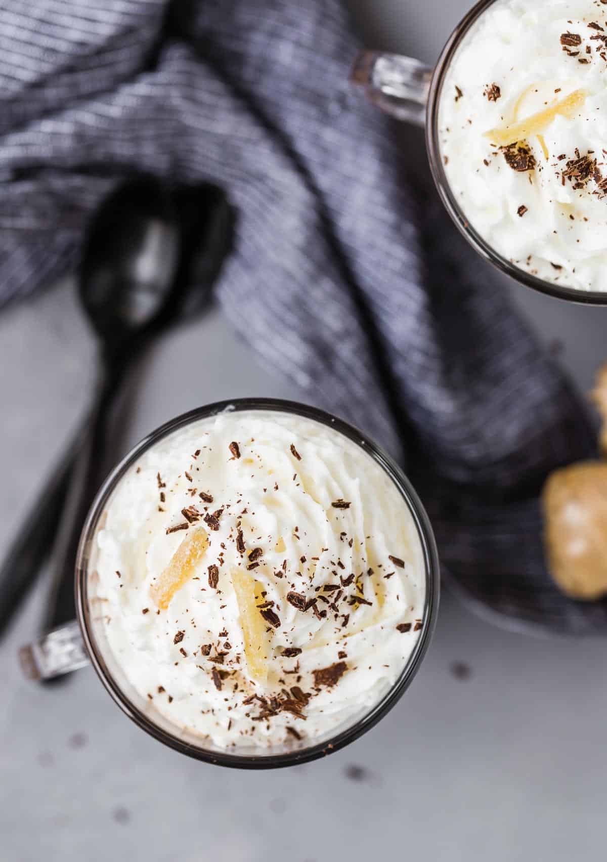 Overhead view of whipped cream in mugs. Spoons also visible.